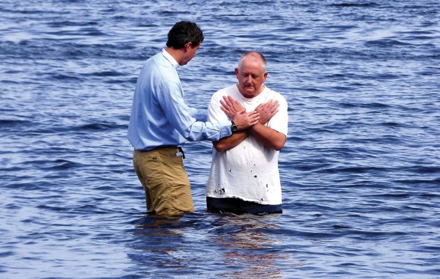 Gathering at the river, local pastor baptizes by immersion Gathering at the river, local pastor baptizes by immersion