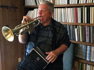 Paul Kurtz with his electronic braille device and trumpet