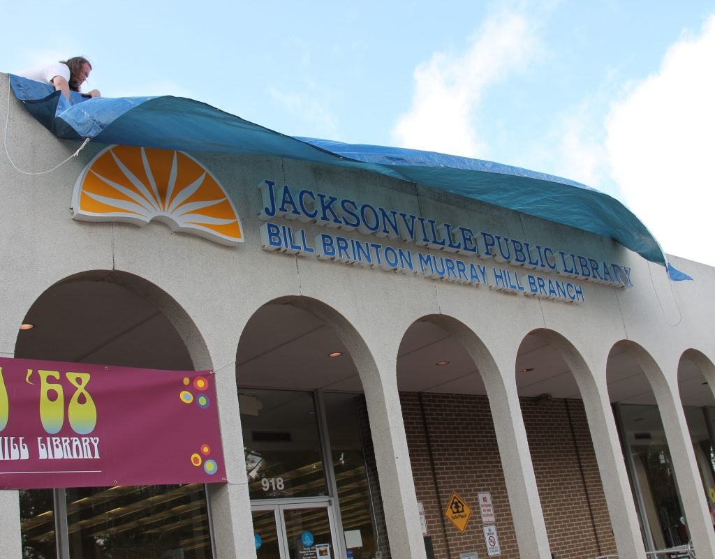 The wind threatened to spoil the reveal of the new name for the Murray Hill Branch Library.