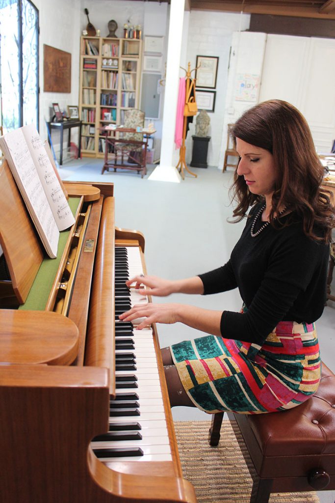 Arjola Miruku in front of her treasured practice piano, given to her by her favorite teacher, Dr. Gary Wolf.