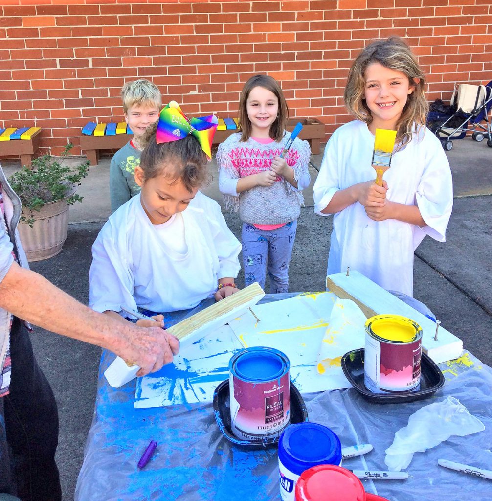 First grade students Gracie Gilley, Knox Harrell, Hallie Snowden and Isabelle Bowman help paint benches in the school colors.