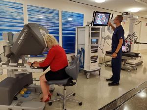 Dutchen Oclon, administrative assistant to Dr. Stephen Buckley, tests out the da Vinci® Surgical System while Weston Snow, a clinical territory associate for Intuitive Surgical, maker of the da Vinci® robot, watches her progress on the big screen.