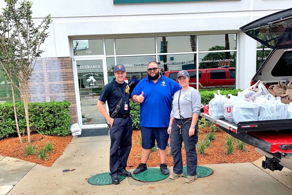 Basim Tannous, center, who owns Palms Café & Catering, stands with two first responders and a truckload of prepared meals during Hurricane Dorian.