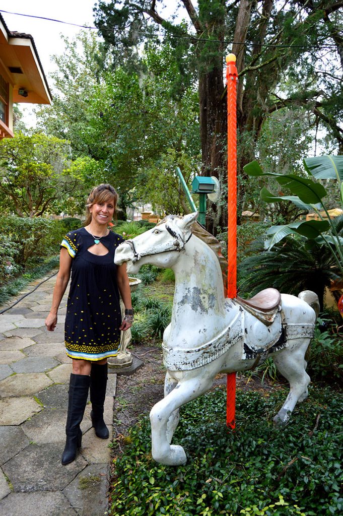 Lana Shuttleworth stands beside a carousel horse along the Cherry Walk near her home