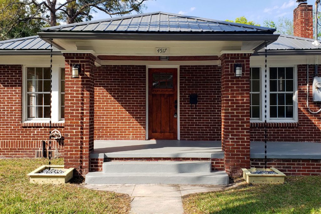 Lunn built wood caps and installed carriage lights for the brick columns, replaced deteriorated facia and soffit boards before the metal roof was installed, and added a stained beadboard ceiling and rain chains.