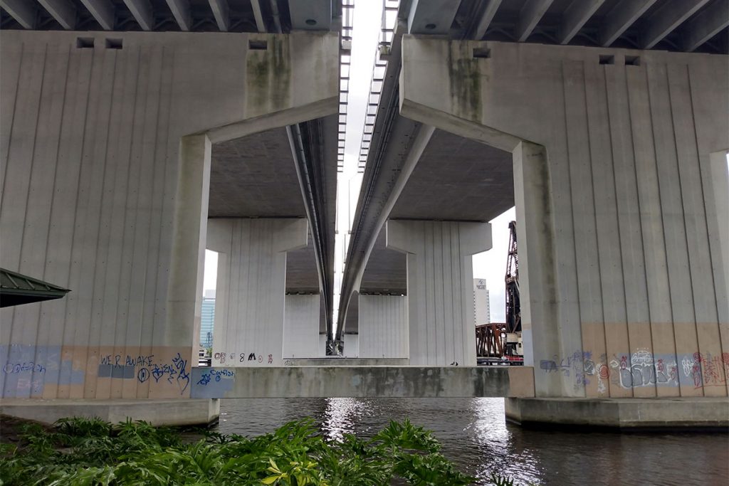 Graffiti covered Acosta Bridge support next to Corkscrew Park on Northbank Riverwalk