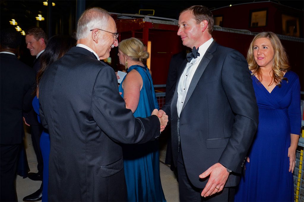 Mike Hightower shakes hands with Tyler Mathews, Immediate Past Chair of the Hightower Fellowship, as Tyler’s wife, Ashford Mathews, looks on.