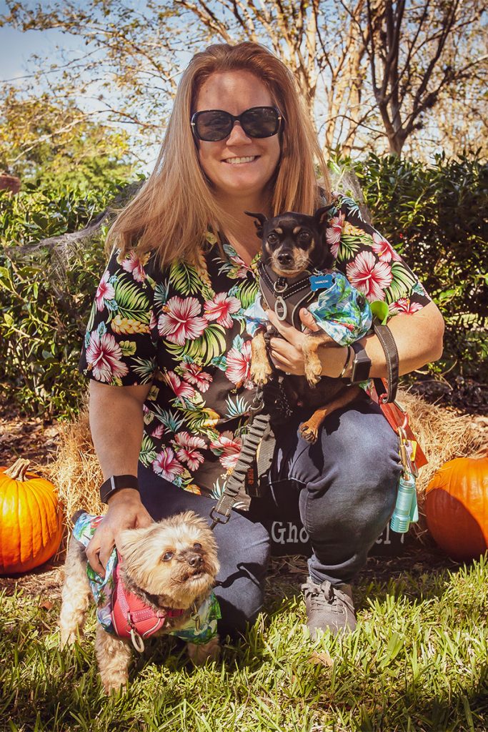 Stacey Steiner outside with two dogs and and two small pumpkins on ground