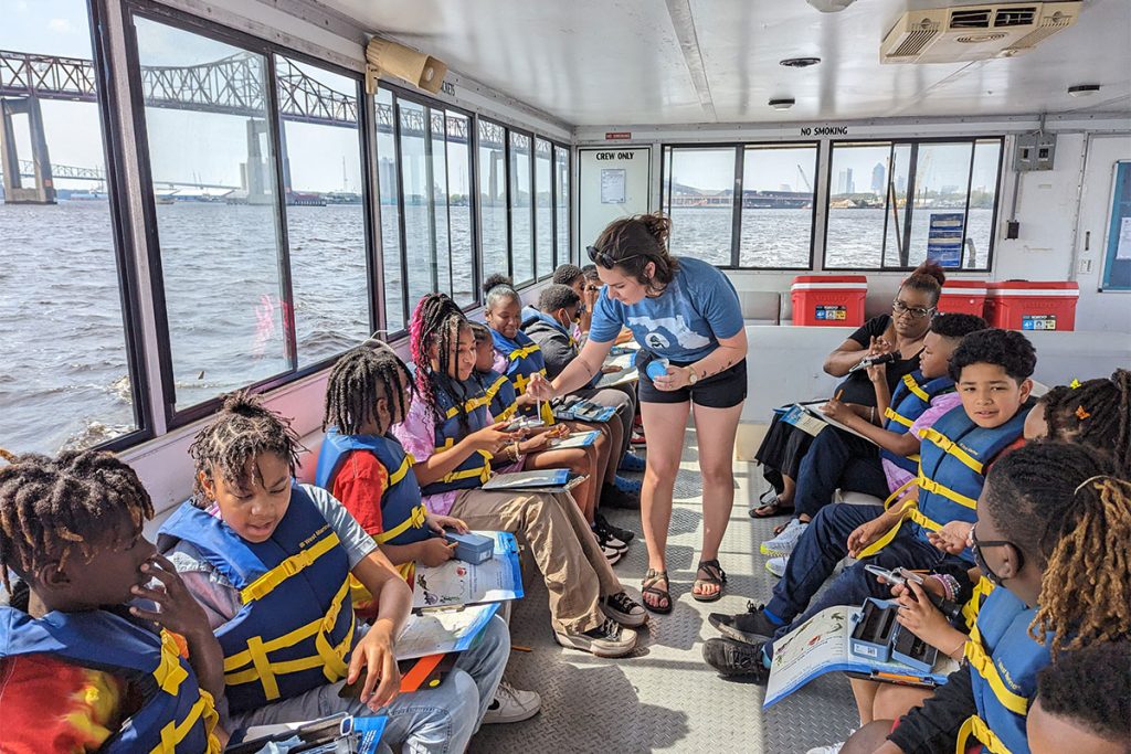 Education Specialist Jamie De Nisco gives out water samples for the students to test river salinity using refractometers.