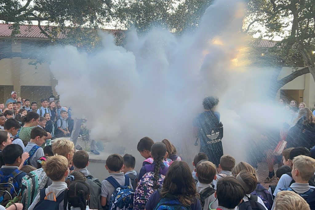 large crowd of kids around statue with fogginess