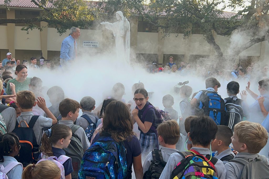 large crowd of kids around statue with fogginess