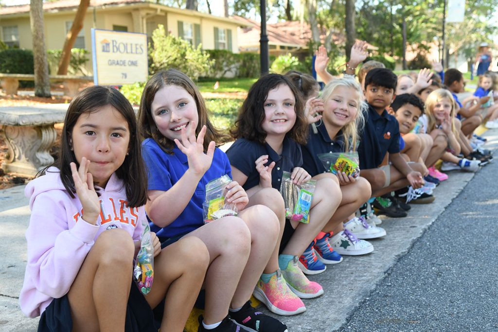 kids sitting on curb, smiling and waving