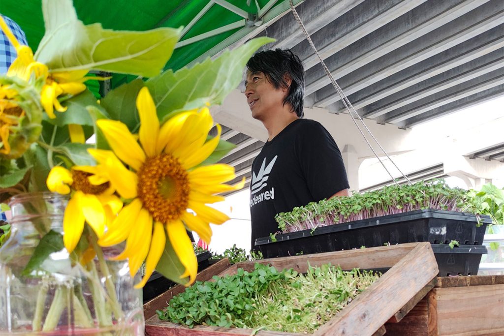 Dave Misola smiling with flowers and vegetables on display