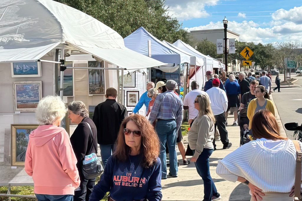 crowd browsing art in display tents at festival