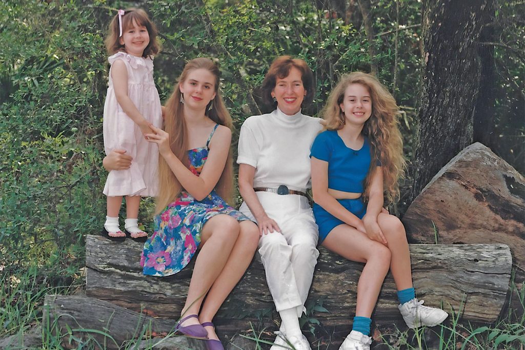 generational female family photo sitting on chopped log in front of trees
