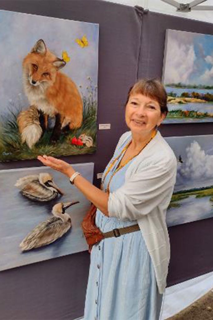 Laurel showing her paintings on display at the Arts Market