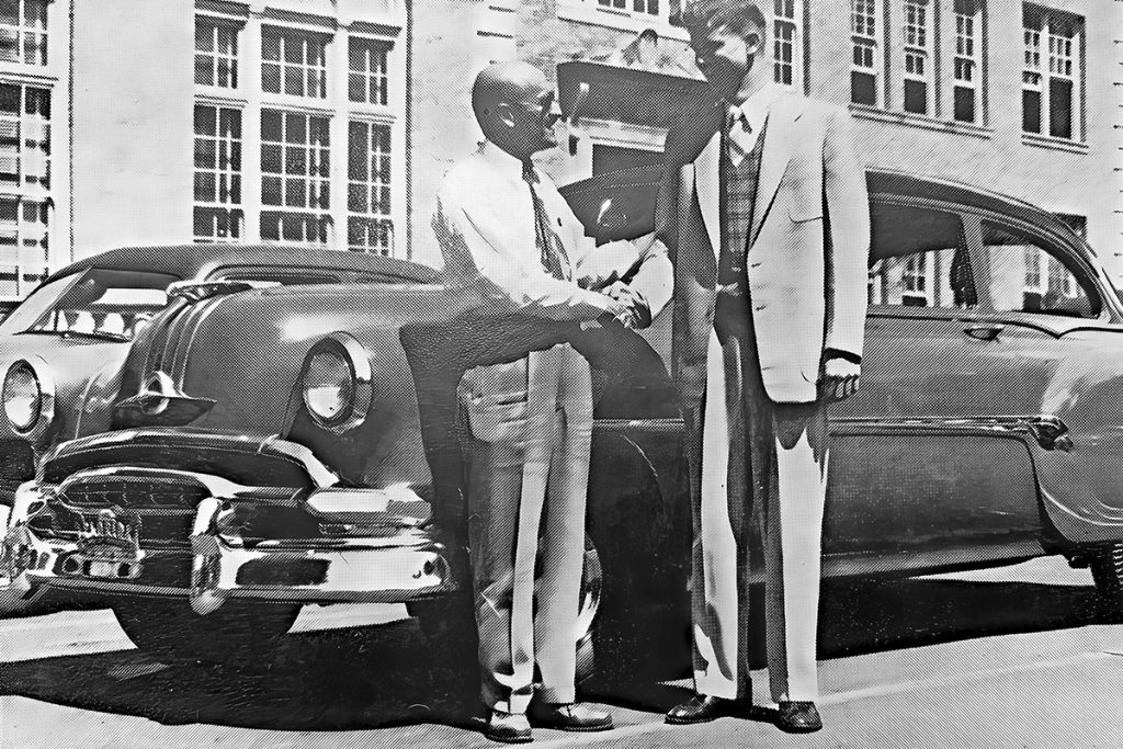 Mr. B.B. Mendoza congratulates Budd Porter on winning a new car in the statewide driving competition.