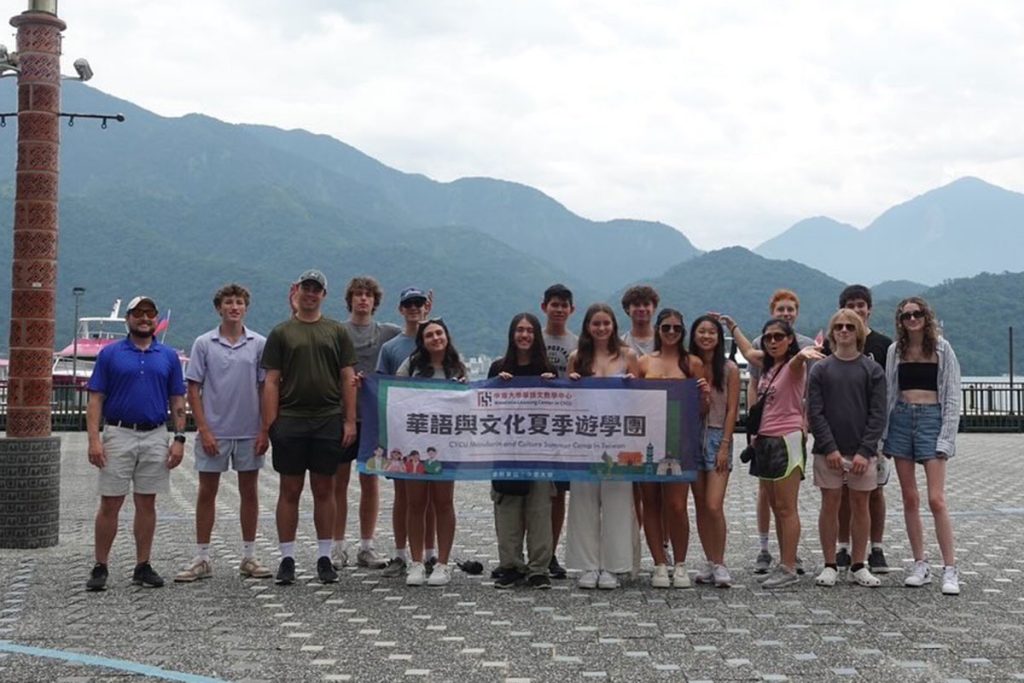 group of students in Taiwan holding banner, with mountains in background